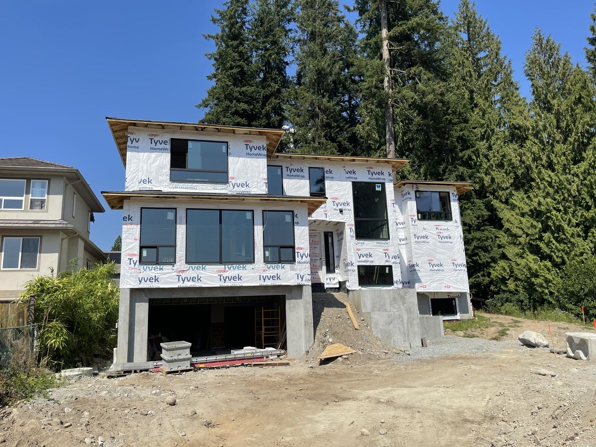 Modern three-level home at lock-up stage, wrapped and windows in, on Burke Mountain